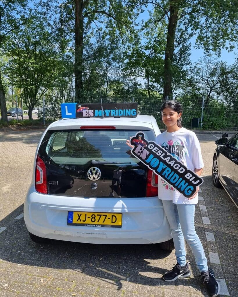 Geslaagde leerling van Rijschool EnjoyRiding poseert trots met certificaat bij lesauto Geslaagde leerling van Rijschool EnjoyRiding poseert trots met certificaat bij lesauto